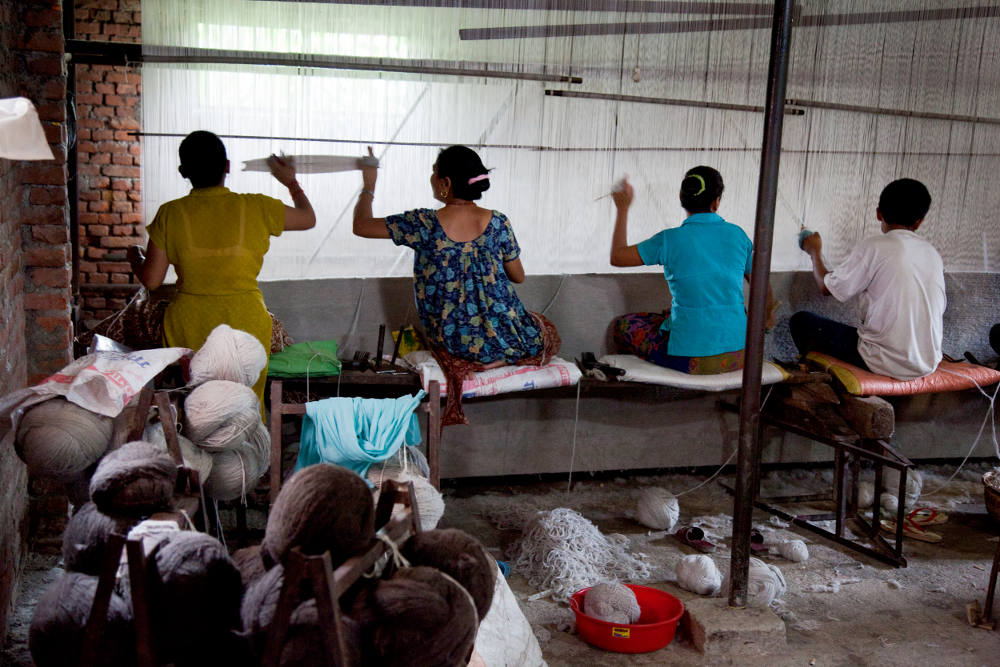 Four people weaving textiles.
