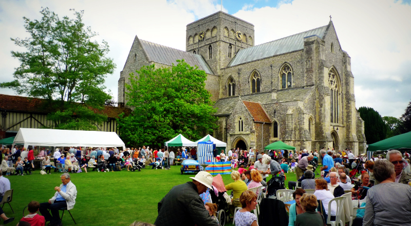Marquees and groups of people in the grounds around a large church.