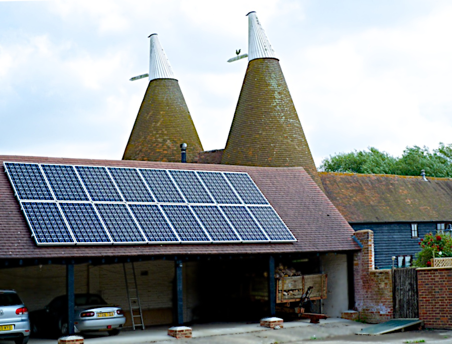 Solar panels on the roof of a building attached to an oast house.