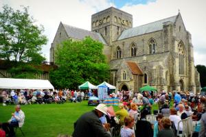 Marquees and groups of people in the grounds around a large church.