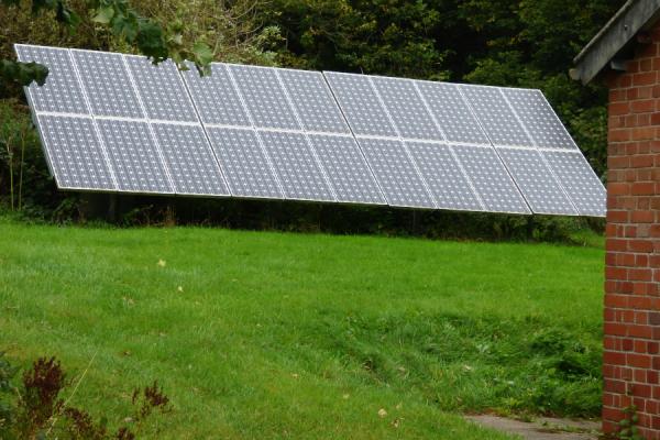 A solar array on the ground behind a brick building.