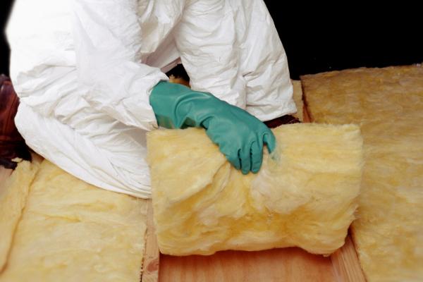 A close-up of a person laying mineral wool battens.